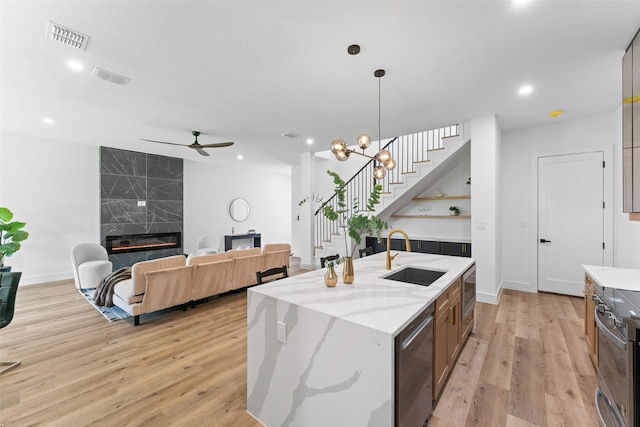 2828 Rochester St, Dallas, TX 75215 - kitchen featuring stainless steel appliances, a ceiling fan, an island with sink, light wood-type flooring, and pendant lighting