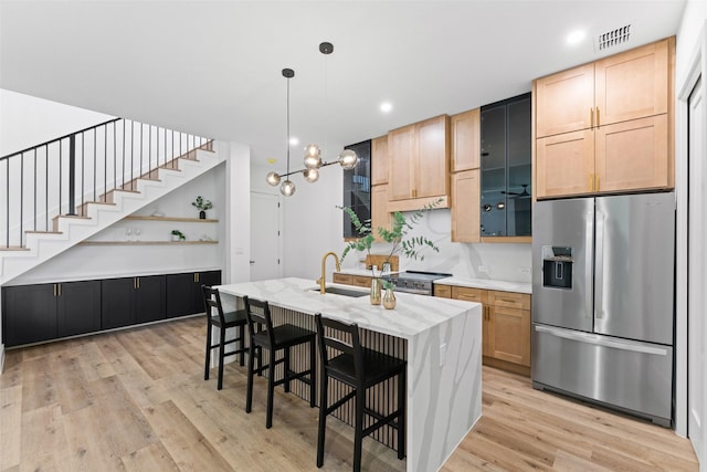 2828 Rochester St, Dallas, TX 75215 - kitchen with stainless steel appliances, light wood-type flooring, open shelves, a breakfast bar, and an island with sink