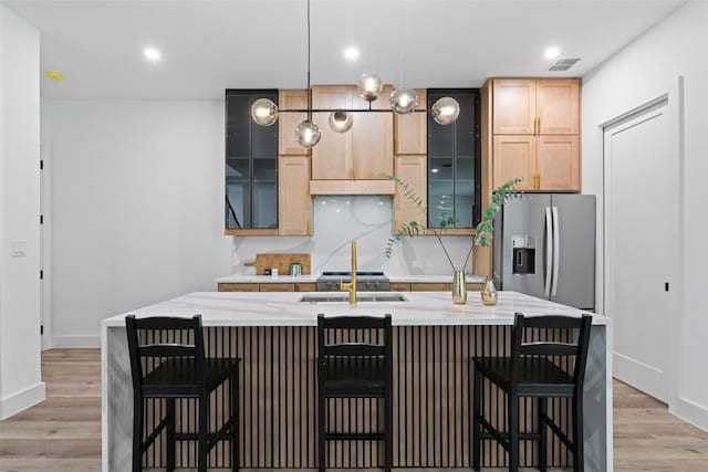 2828 Rochester St, Dallas, TX 75215 - kitchen with stainless steel fridge, an island with sink, light wood-type flooring, glass insert cabinets, and recessed lighting