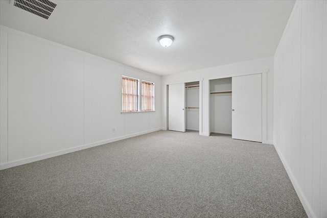 416 W 3rd St, Justin, TX 76247 - unfurnished bedroom featuring two closets, carpet floors, and a textured ceiling