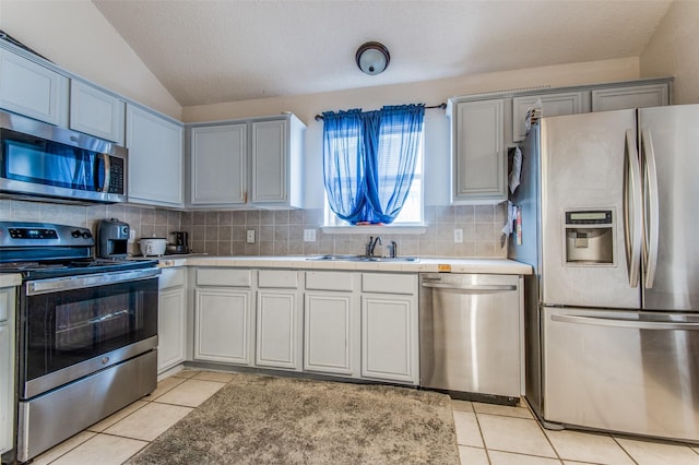 1008 Brook Cyn, Arlington, TX 76018 - kitchen with stainless steel appliances, lofted ceiling, light tile patterned flooring, backsplash, and tile countertops