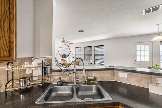 9507 Tallow Berry Dr, Dallas, TX 75249 - kitchen with decorative backsplash, dark countertops, ceiling fan, a textured ceiling, and hanging light fixtures