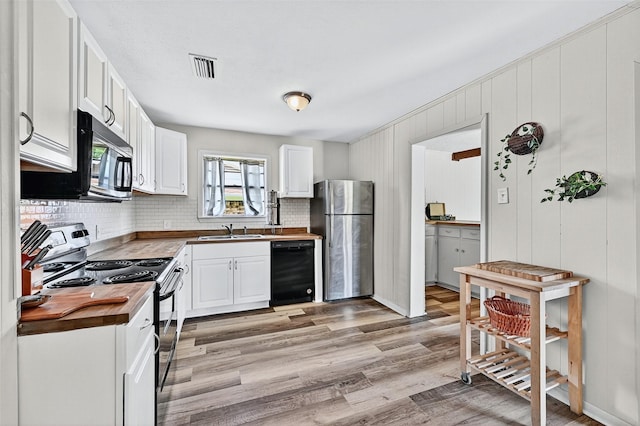 1031 Patricia Dr, Sherman, TX 75090 - kitchen with black appliances, tasteful backsplash, light wood-type flooring, and white cabinetry