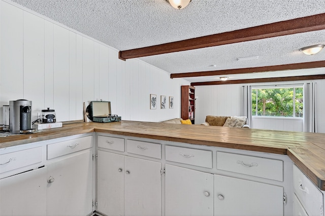 1031 Patricia Dr, Sherman, TX 75090 - kitchen featuring wooden counters, a textured ceiling, beam ceiling, and white cabinets