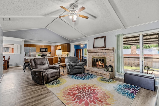 910 Meadowside Cir, Garland, TX 75043 - living room featuring a ceiling fan, wood finished floors, vaulted ceiling, a fireplace, and a textured ceiling