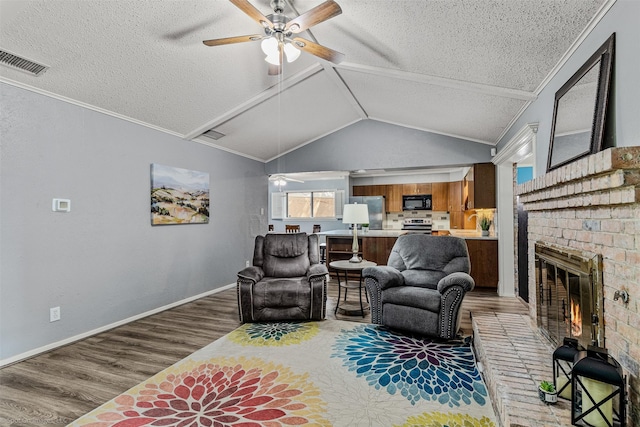 910 Meadowside Cir, Garland, TX 75043 - living room with ceiling fan, a textured ceiling, wood finished floors, a brick fireplace, and lofted ceiling