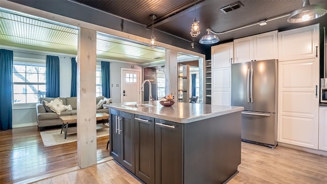1250 N Isla St, Stephenville, TX 76401 - kitchen featuring freestanding refrigerator, white cabinets, open floor plan, light wood-style flooring, and an island with sink