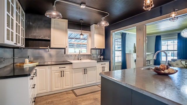 1250 N Isla St, Stephenville, TX 76401 - kitchen featuring dark countertops, light wood finished floors, glass insert cabinets, and plenty of natural light