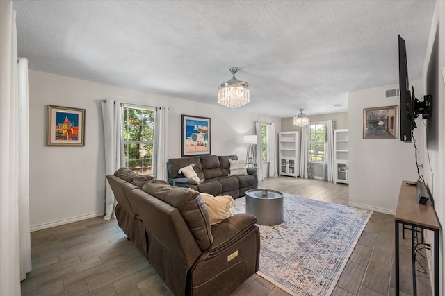 7720 Angelina Dr, Athens, TX 75752 - living room with a chandelier, wood finished floors, and a textured ceiling