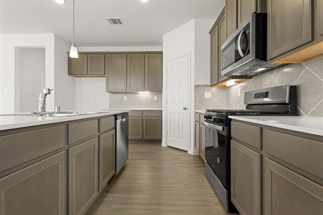 469 Silent Pond, Lavon, TX 75166 - kitchen with appliances with stainless steel finishes, wood finished floors, light countertops, pendant lighting, and backsplash