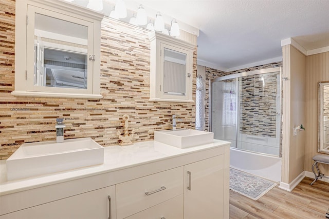 4018 Linda Ct, Granbury, TX 76048 - bathroom featuring double vanity, wood finished floors, decorative backsplash, combined bath / shower with glass door, and crown molding
