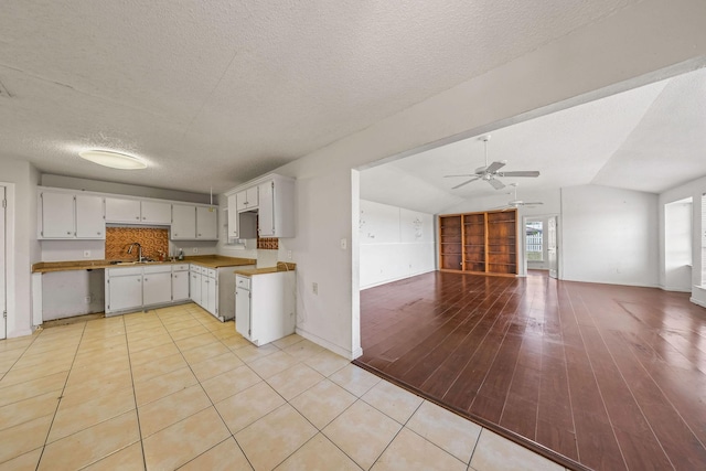 101 Arrowhead St, Fort Worth, TX 76108 - kitchen featuring ceiling fan, open floor plan, lofted ceiling, a textured ceiling, and white cabinetry