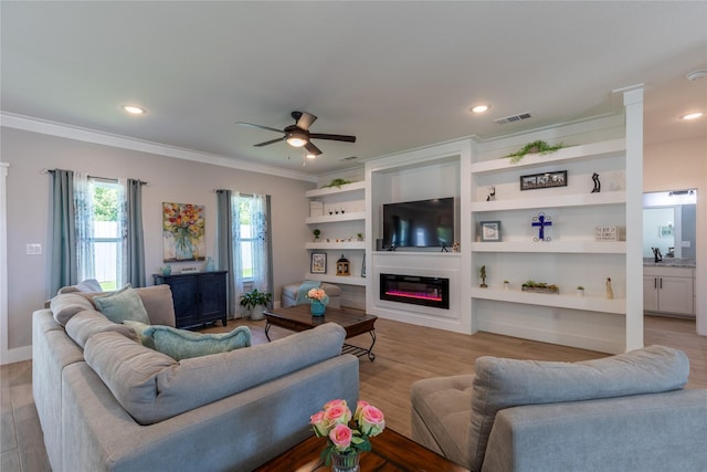 5523 Firewood Trl, Granbury, TX 76048 - living room with a glass covered fireplace, ornamental molding, a ceiling fan, light wood finished floors, and recessed lighting