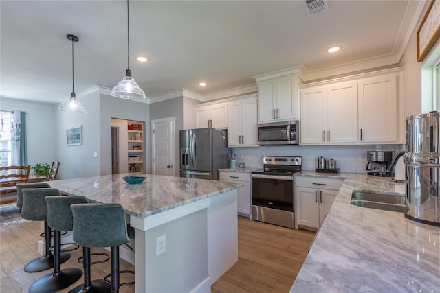 5523 Firewood Trl, Granbury, TX 76048 - kitchen with stainless steel appliances, crown molding, a kitchen island, tasteful backsplash, and light stone countertops