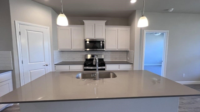 1821 Brindle St, Northlake, TX 76247 - kitchen with stainless steel appliances, tasteful backsplash, a center island with sink, white cabinetry, and hanging light fixtures