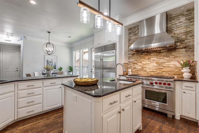4421 Caruth Blvd, Dallas, TX 75225 - kitchen featuring wall chimney range hood, premium appliances, a kitchen island with sink, backsplash, and dark wood-type flooring
