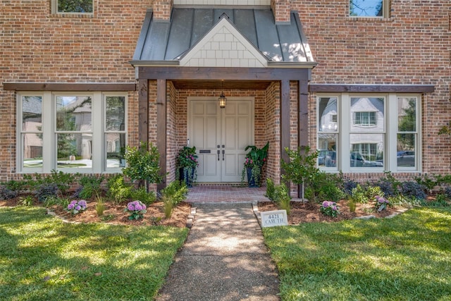 4421 Caruth Blvd, Dallas, TX 75225 - view of exterior entry with brick siding, a standing seam roof, a yard, and a metal roof