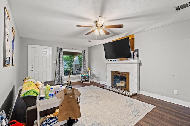 1601 W Bond St, Denison, TX 75020 - living area featuring a ceiling fan, a brick fireplace, dark wood-type flooring, and a textured ceiling