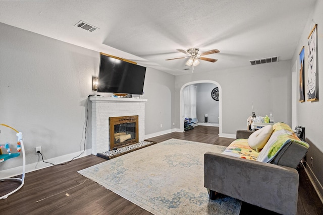 1601 W Bond St, Denison, TX 75020 - living area featuring arched walkways, a ceiling fan, dark wood finished floors, and a brick fireplace