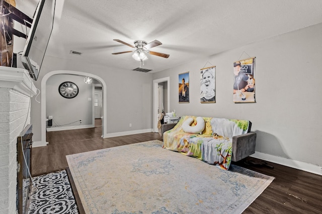 1601 W Bond St, Denison, TX 75020 - living room with ceiling fan, wood finished floors, arched walkways, a fireplace, and a textured ceiling