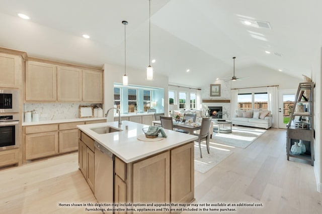 209 Dove Haven Dr, Wylie, TX 75098 - kitchen featuring light brown cabinetry, appliances with stainless steel finishes, a ceiling fan, a fireplace, and light wood-style floors