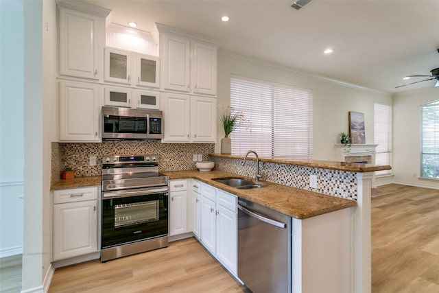 661 Raintree Cir, Coppell, TX 75019 - kitchen with stainless steel appliances, a peninsula, tasteful backsplash, light wood-style flooring, and ornamental molding