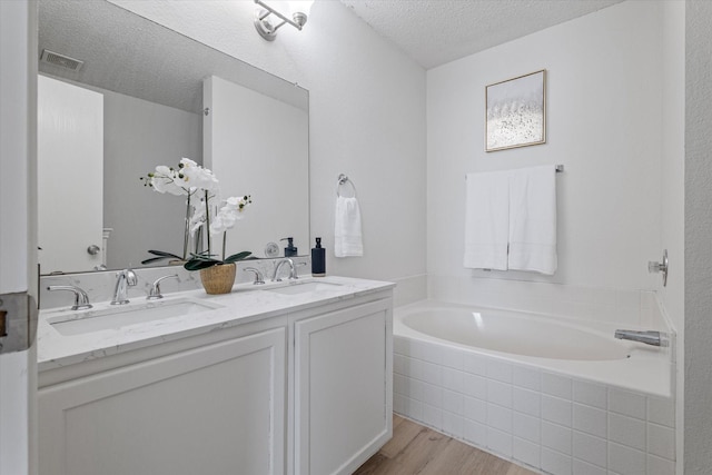 3300 Jacobs Dr, Mckinney, TX 75070 - full bath featuring wood finished floors, a textured ceiling, a bath, and double vanity