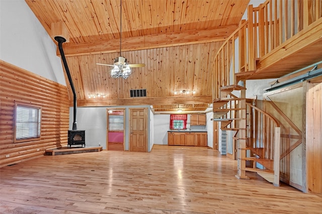 570 Roy Ayres Rd, Bells, TX 75414 - unfurnished living room with a wood stove, log walls, ceiling fan, high vaulted ceiling, and stairway