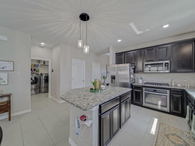 2460 Open Range Dr, Fort Worth, TX 76177 - kitchen featuring stainless steel appliances, separate washer and dryer, light tile patterned floors, light stone counters, and backsplash