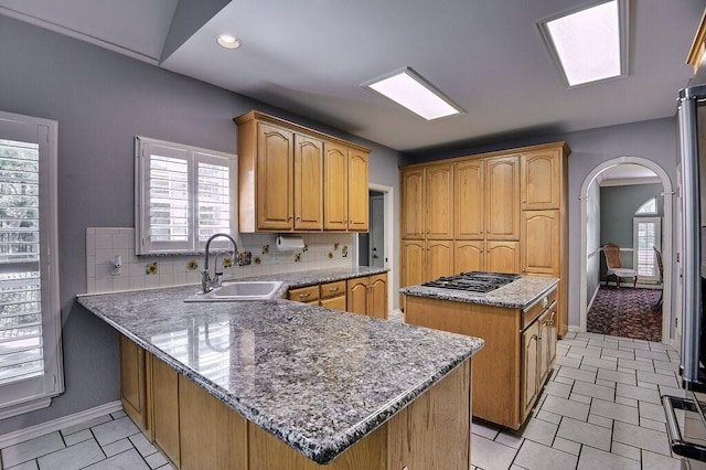836 Nueces Trl, Midlothian, TX 76065 - kitchen featuring stainless steel gas stovetop, arched walkways, a center island, a peninsula, and light stone counters