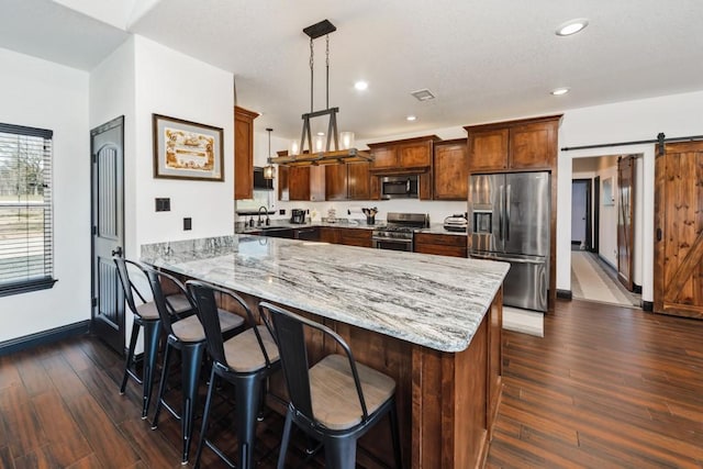 217 Polk, Bowie, TX 76230 - kitchen with stainless steel appliances, a peninsula, light stone counters, dark wood finished floors, and a barn door