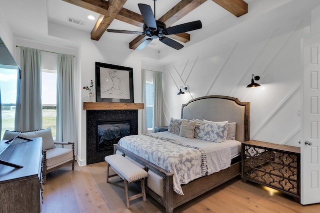 140 Friesian Ln, Waxahachie, TX 75167 - bedroom with coffered ceiling, light wood finished floors, beamed ceiling, a glass covered fireplace, and a ceiling fan