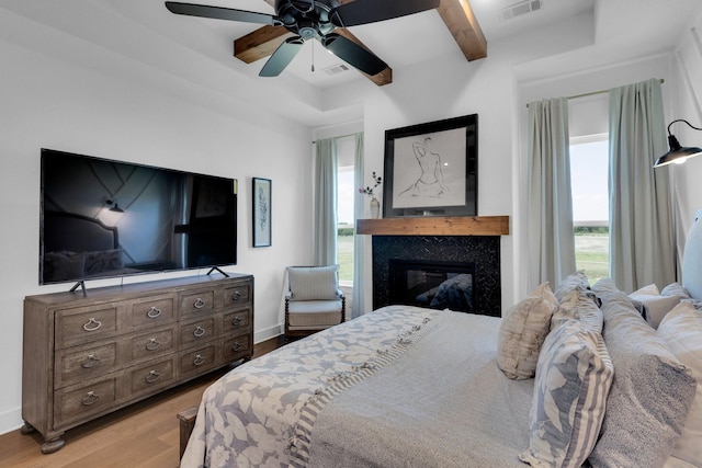 140 Friesian Ln, Waxahachie, TX 75167 - bedroom with light wood-style flooring, multiple windows, a premium fireplace, beam ceiling, and ceiling fan