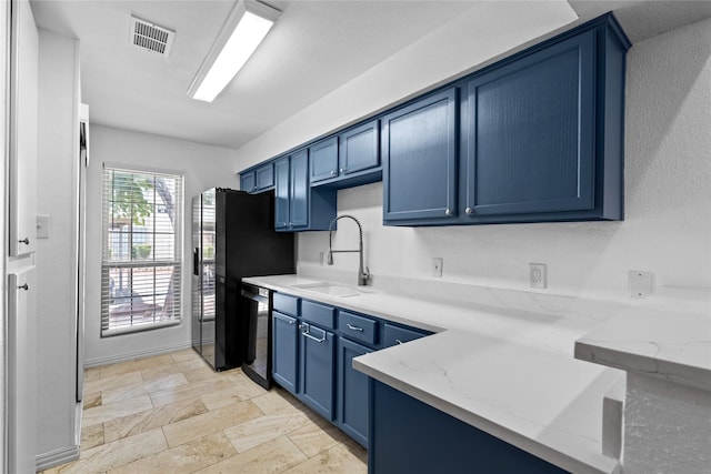 350 W Harwood Rd Unit A, Hurst, TX 76054 - kitchen featuring blue cabinets, light stone counters, stone tile floors, stainless steel dishwasher, and freestanding refrigerator