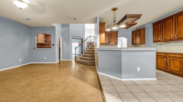 5613 Buttercup Ln, Mckinney, TX 75070 - kitchen with arched walkways, decorative backsplash, brown cabinets, light stone countertops, and pendant lighting