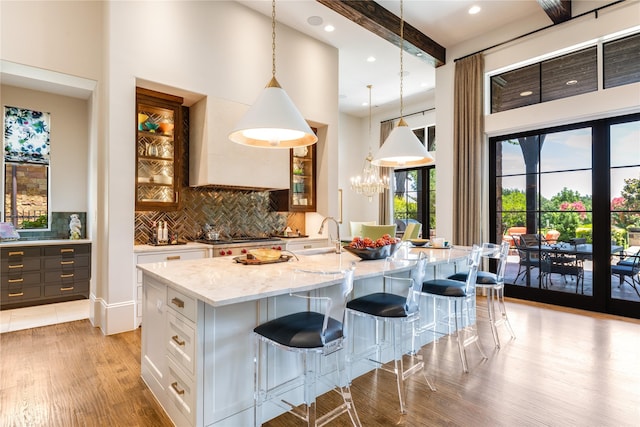 2307 Cedar Elm Ter, Westlake, TX 76262 - kitchen with light stone countertops, a high ceiling, light wood-style floors, glass insert cabinets, and tasteful backsplash