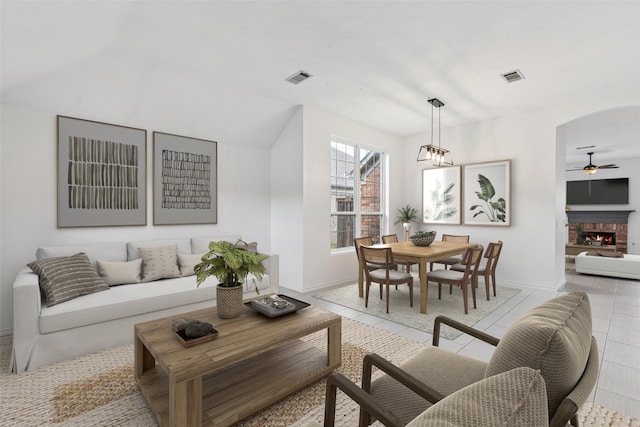 10412 Harris Ct, Irving, TX 75063 - living room with ceiling fan, light tile patterned floors, a fireplace, arched walkways, and vaulted ceiling