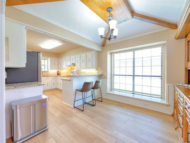 2219 Timberwood, Carrollton, TX 75006 - kitchen with freestanding refrigerator, a chandelier, tasteful backsplash, a peninsula, and light wood finished floors