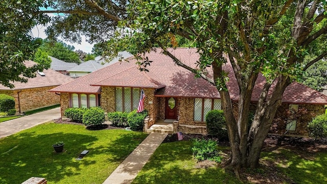 1115 Shady Oak Trl, Mansfield, TX 76063 - tudor home featuring roof with shingles, a front lawn, concrete driveway, and brick siding