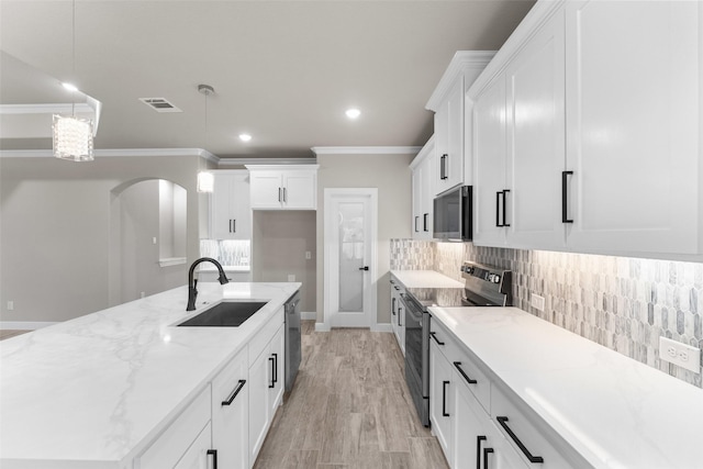 1806 Ave F, Dallas, TX 75051 - kitchen featuring appliances with stainless steel finishes, backsplash, light stone counters, white cabinetry, and crown molding