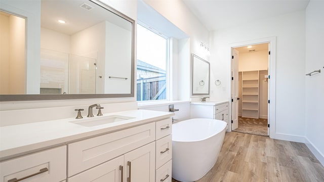 14848 Grissom Ave, Aledo, TX 76008 - bathroom featuring a stall shower, wood finished floors, two vanities, a freestanding bath, and a spacious closet