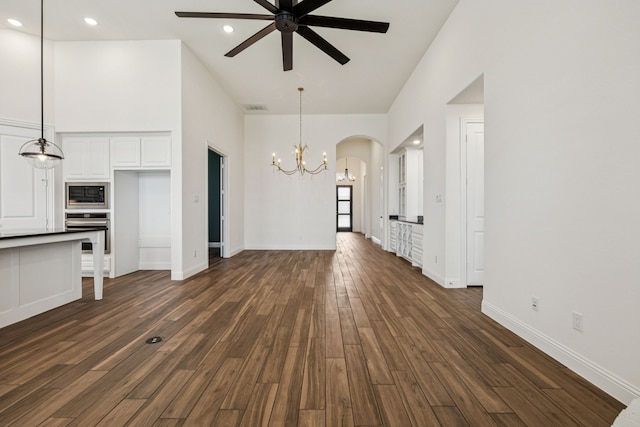 1713 Purple Thistle Ln, Fort Worth, TX 76008 - unfurnished living room with a chandelier, a ceiling fan, dark wood-style floors, arched walkways, and a high ceiling
