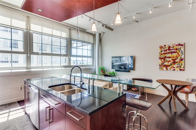 2600 W 7th St Unit 1417, Fort Worth, TX 76107 - kitchen featuring track lighting, a center island with sink, stainless steel dishwasher, dark stone counters, and hanging light fixtures