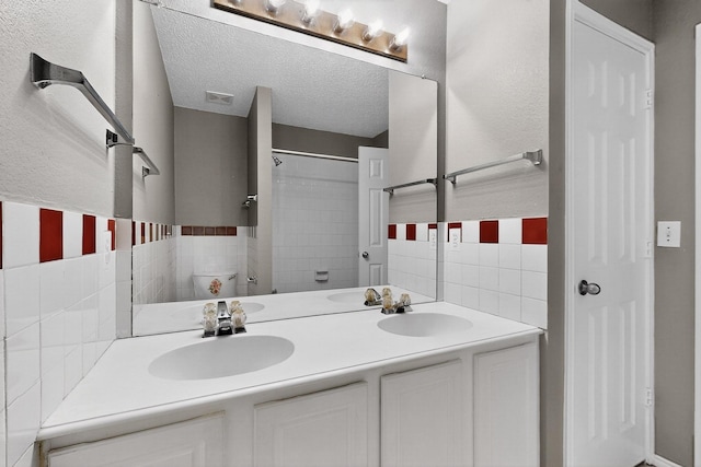 8409 Vicksburg Ln, Fort Worth, TX 76123 - bathroom with tile walls, double vanity, a textured ceiling, and a shower