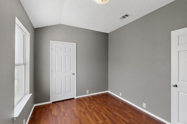 8409 Vicksburg Ln, Fort Worth, TX 76123 - unfurnished bedroom with multiple windows, wood finished floors, lofted ceiling, and a textured ceiling