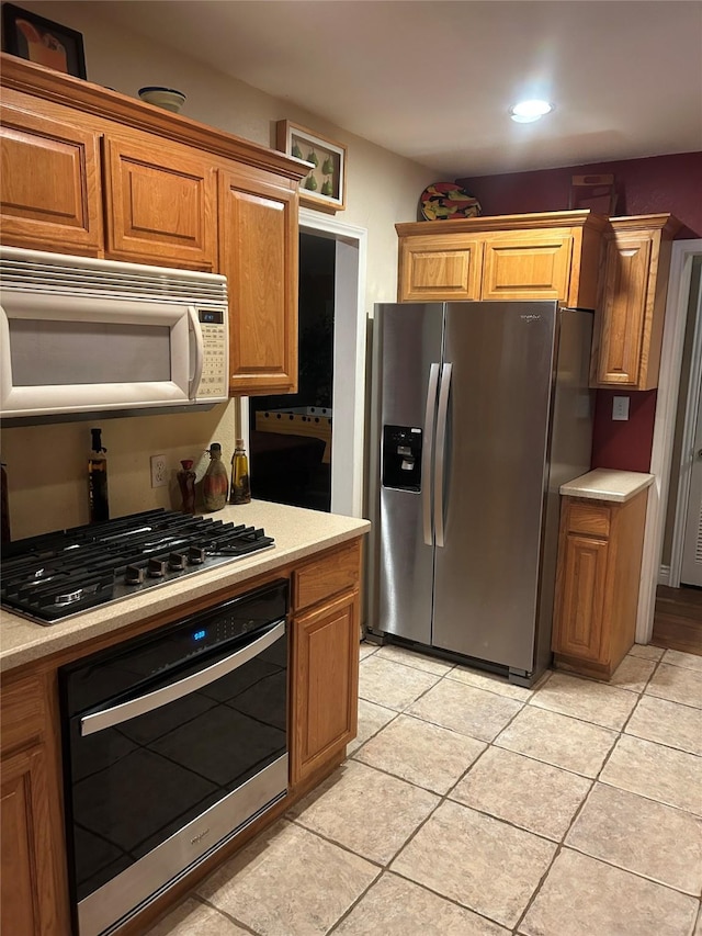 625 N Bailey Ave, Fort Worth, TX 76107 - kitchen with appliances with stainless steel finishes, light countertops, brown cabinetry, light tile patterned floors, and recessed lighting