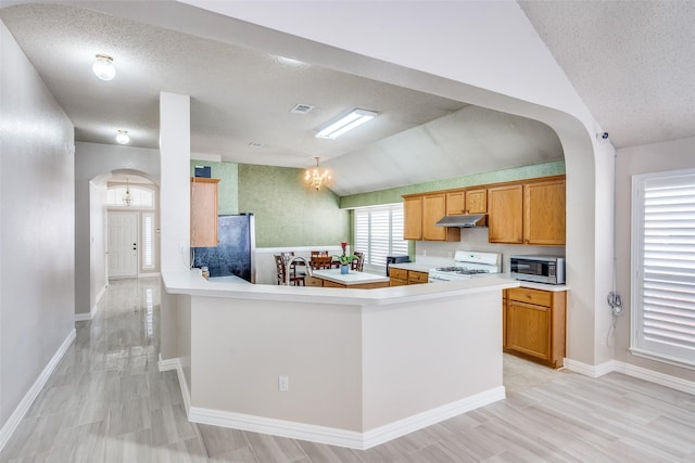 7012 Hillshire Ln, Sachse, TX 75048 - kitchen featuring stainless steel appliances, lofted ceiling, arched walkways, light countertops, and a textured ceiling