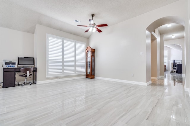 7012 Hillshire Ln, Sachse, TX 75048 - unfurnished living room with arched walkways, ceiling fan, an office area, healthy amount of natural light, and a textured ceiling