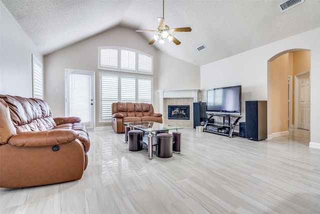 7012 Hillshire Ln, Sachse, TX 75048 - living area with arched walkways, ceiling fan, a fireplace, vaulted ceiling, and a textured ceiling