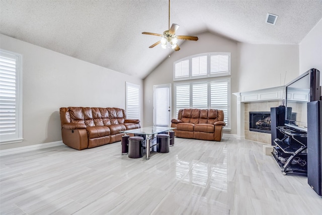7012 Hillshire Ln, Sachse, TX 75048 - living room with ceiling fan, a fireplace, a textured ceiling, high vaulted ceiling, and light wood finished floors